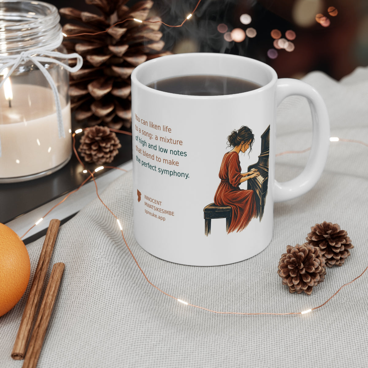White Life as a Song mug styled beside a candle and pinecones, featuring an orange-clad piano player.