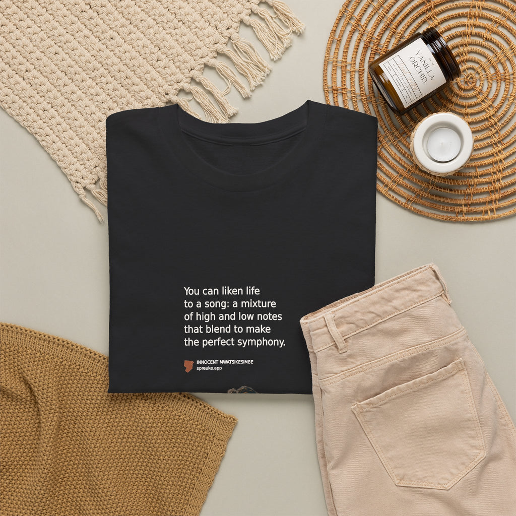 Folded black Life as a Song T-shirt styled beside beige trousers.