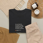 Folded black Life as a Song T-shirt styled beside beige trousers.